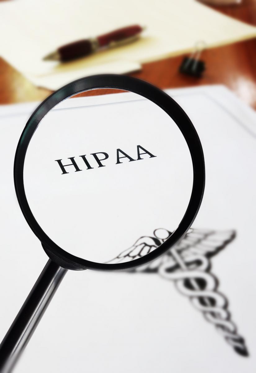 Magnifying glass surrounding the word "HIPAA" on a file